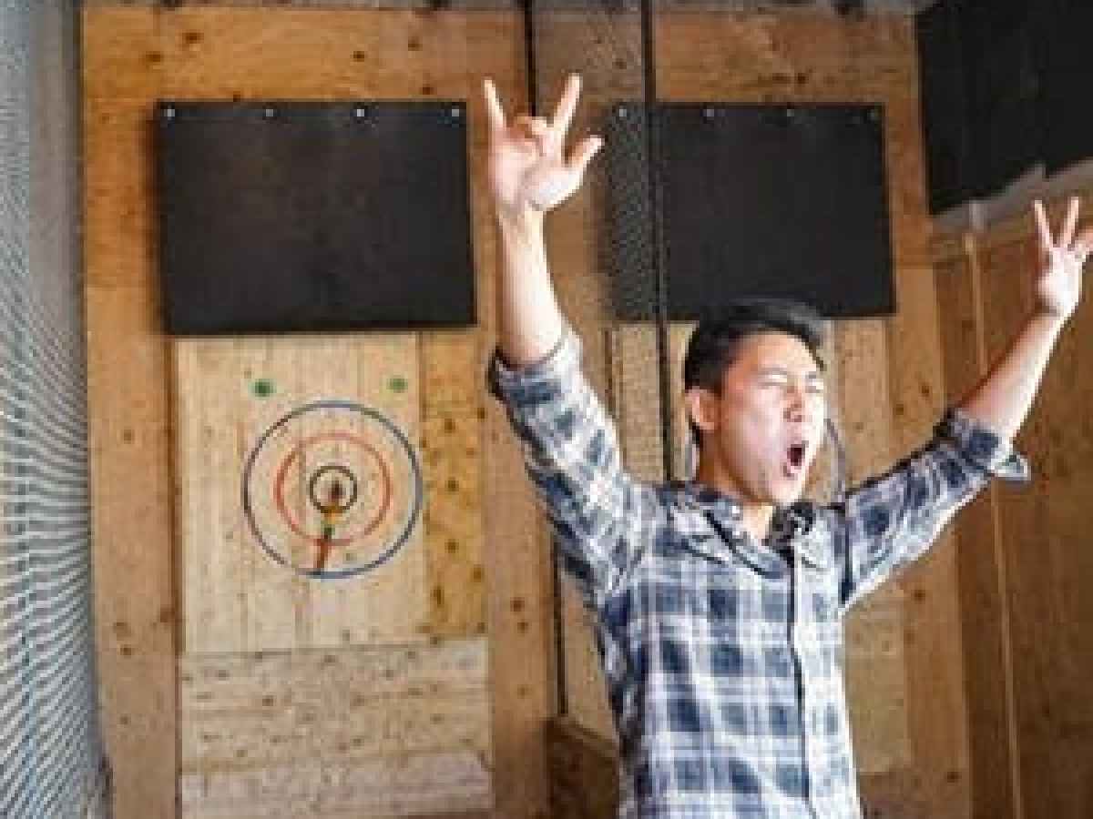 A man celebrates with hands up in the air at Forged Axe throwing