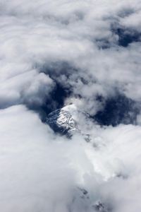 Clouds flowing over the top of a snowy mountain