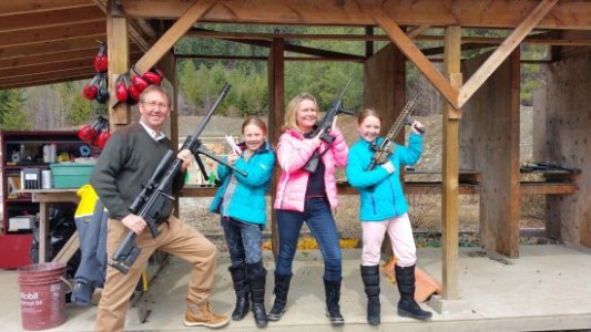 parents pose with their children, holding guns, at the Whistler Gun Range