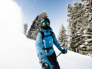 Man skiing with go pro on selfie stick in powder.