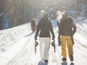 Two people walk a trail with snowshoes